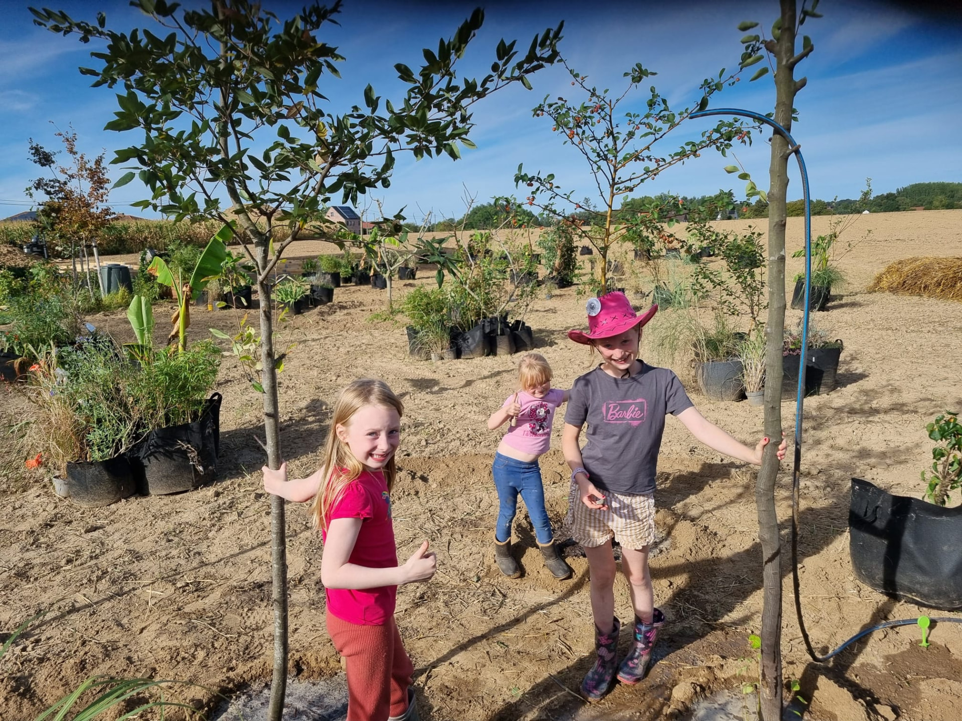 Kinderen houden jonge bomen recht tijdens het planten